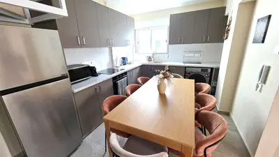 a kitchen with a wooden table and chairs in it at 3BR Shared Apt - Beach 7-min walk, Peaceful in Larnaka