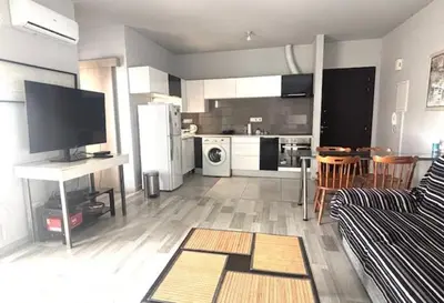 a living room with a couch and a kitchen at Spacious 1 bedroom apartment with an attic bedroom in Strovolos