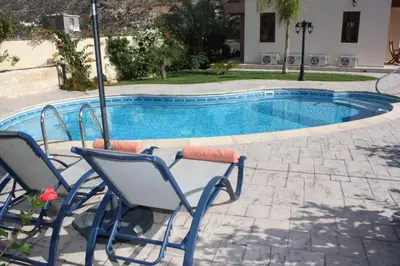a pool with chairs and an umbrella next to it at Luxury Villa Rental, Two Bedroom Villa with private pool and garden, in Pissouri