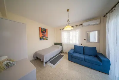 a living room with a blue couch and a bed at The Nissi Duo Collection in Ayia Napa