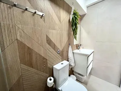 a bathroom with a white toilet and a wooden wall at STAY Blue House in Larnaka