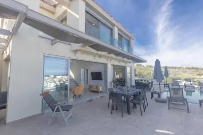 a patio with a table and chairs and a pool at Living the View in Protaras