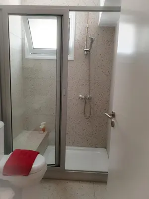 a bathroom with a shower and a toilet with a window at Rainbow Apartments in Ayia Napa