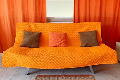 an orange couch with three pillows on it at Rainbow Apartments in Ayia Napa