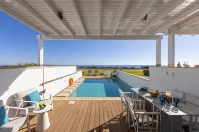 a patio with a pool and a table and chairs at Protaras Seafront Villa Galene Del Mar in Protaras
