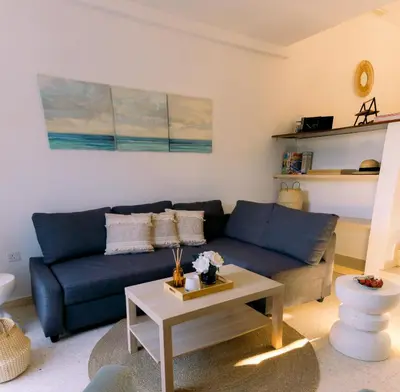 a living room with a blue couch and a coffee table at Kymo Fig Tree Bay House in Protaras