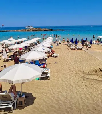 a beach with many umbrellas and people in the water at Protaras Sol 2 Bedroom Holiday Let Apartment in Protaras