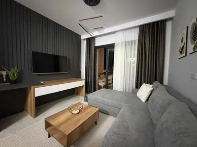 a living room with a gray couch and a tv at Riverside Life residence in Long Beach, Iskele, North Cyprus in Dherinia