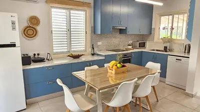 a kitchen with blue cabinets and a wooden table and chairs at Andreotis Garden in Protaras