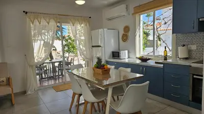 a kitchen with a table and chairs and a kitchen with blue cabinets at Andreotis Garden in Protaras