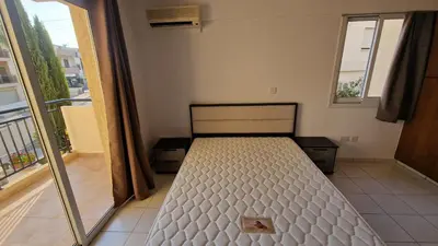 a bed in a room with two windows at Limassol Great in Limassol