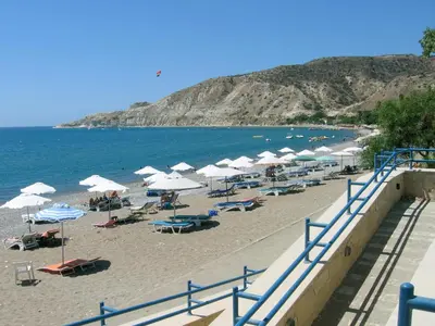 a beach with umbrellas and chairs and the ocean at The Love Nest in Pissouri