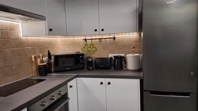 a kitchen with white cabinets and a stainless steel refrigerator at Nissi Golden Sands Paradi in Ayia Napa