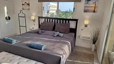a bedroom with a large bed with blue pillows at Nissi Golden Sands Paradi in Ayia Napa