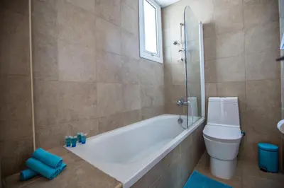 a bathroom with a tub and a toilet and a window at Seaspray in Protaras