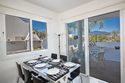 a dining room with a table and chairs and a balcony at Flouressia Villa 4 in Protaras