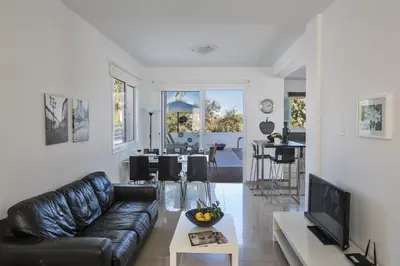 a living room with a black leather couch and a tv at Flouressia Villa 4 in Protaras
