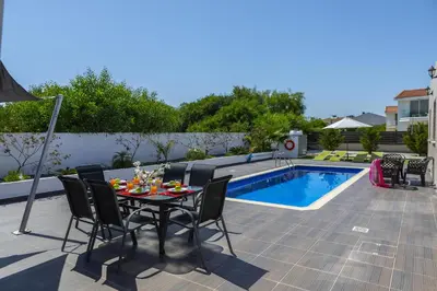 a patio with a table and chairs next to a pool at Protaras Villa Hollywood in Protaras