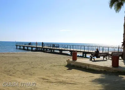 a person sitting on a bench near a pier at Ithaki Phinikoudes Apartment 307 in Larnaka