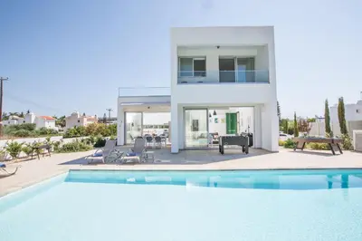 a villa with a swimming pool in front of a house at Greco Villas in Protaras
