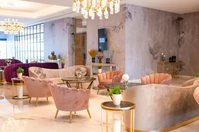 a lobby with pink chairs and tables and a chandelier at At Herbal Boutique Hotel & Spa in Protaras