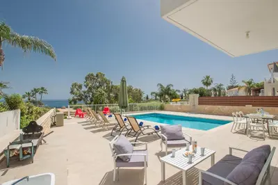 a patio with a pool and chairs and a table at Shaye Front Line Villa in Protaras