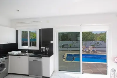 a white kitchen with a view of a pool at Broadway Villas in Protaras