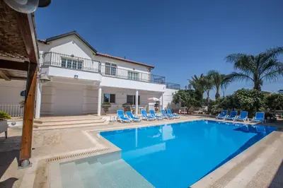 a swimming pool with chairs and a house at Papas Family Villa in Paralimni