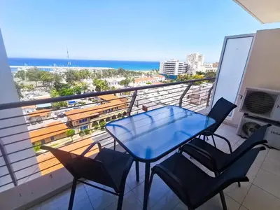 a blue table and chairs on a balcony with the beach at Paradise Palms Seaview Apartment in Larnaka