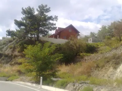 a house on the side of a hill with a road at Agros Timber Log House in Agros
