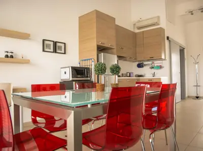 a kitchen with a glass table and red chairs at Olivier Residence in Nicosia