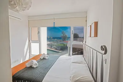 a bedroom with a bed with a view of a balcony at Pallinio Fig Tree Bay Apartments in Protaras