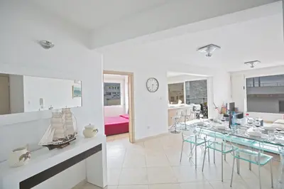 a white dining room with a table and chairs at Pallinio Fig Tree Bay Apartments in Protaras