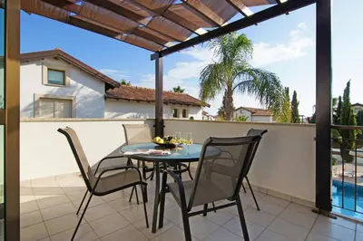 a patio with a table and chairs on a balcony at Villa Regina in Ayia Napa