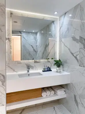 a white bathroom with a sink and a mirror at Ajax Hotel in Limassol