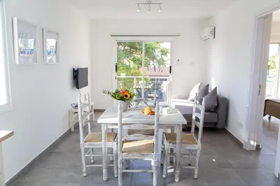 a dining room with a white table and chairs at Tikay Holiday Apts in Ayia Napa