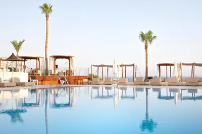 a large swimming pool with chairs and palm trees at Napa Mermaid Hotel & Suites in Ayia Napa