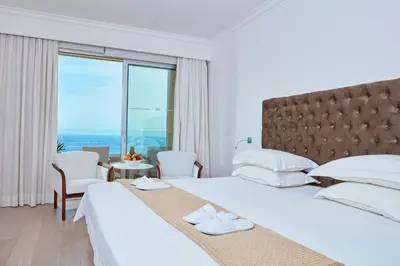 a hotel room with two beds and a large window at Grecian Park in Protaras