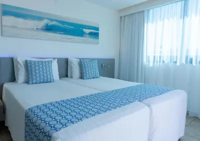 a bedroom with two beds with blue pillows at Anonymous Beach Hotel (Adults 16+) in Ayia Napa
