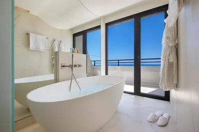 a white tub in a bathroom with a large window at Amathus Beach Hotel Limassol in Limassol