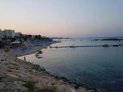 a beach with a group of boats in the water at Astreas Beach Hotel Apartments in Protaras