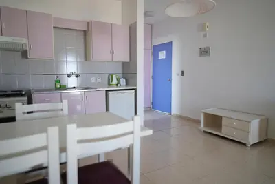 a kitchen with purple cabinets and a blue door at Astreas Beach Hotel Apartments in Protaras