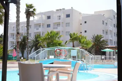 a pool with a slide in front of a building at Astreas Beach Hotel Apartments in Protaras