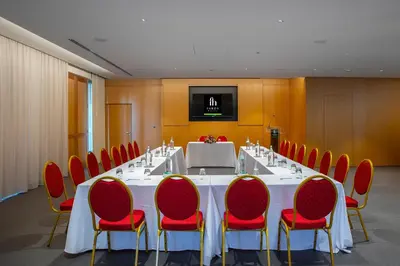 a conference room with a long table and red chairs at Faros Hotel Ayia Napa in Ayia Napa