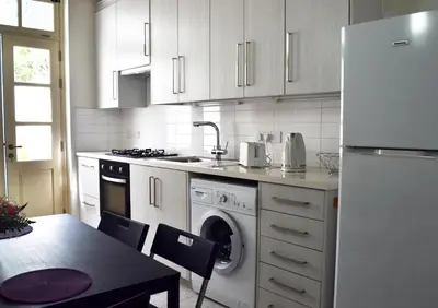 a kitchen with white cabinets and a washer and dryer at Chris House in Nicosia