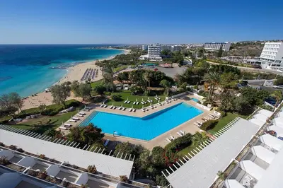 an aerial view of a resort with a swimming pool and the beach at Grecian Sands Hotel in Ayia Napa