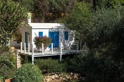 a small white house with blue doors on a dock at Grecian Sands Hotel in Ayia Napa