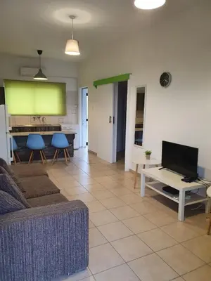 a living room with a couch and a table with a tv at Sea Apartments in Larnaka
