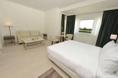 a hotel room with a white bed and a couch at Hilton Nicosia in Nicosia
