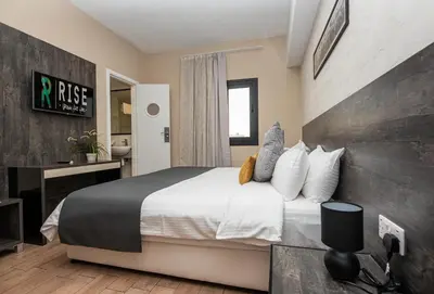 a bedroom with a large bed with white sheets and pillows at Rise Urban Art Hotel in Larnaka